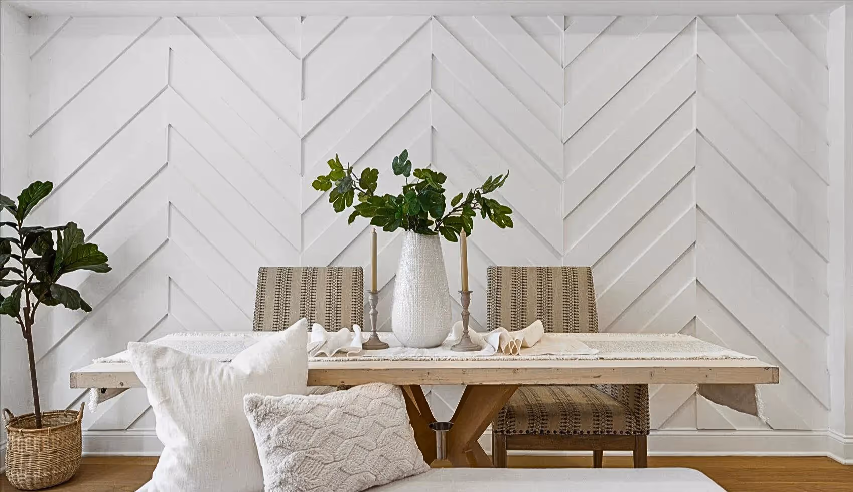 Close-up view of dining area accent wall featuring white wood planks arranged in a striking chevron pattern, adding texture and visual interest to the space.