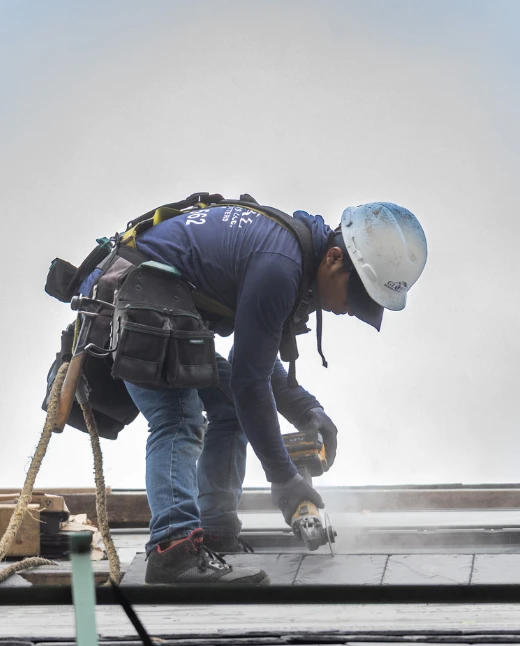 Roofer cutting slate on roof.