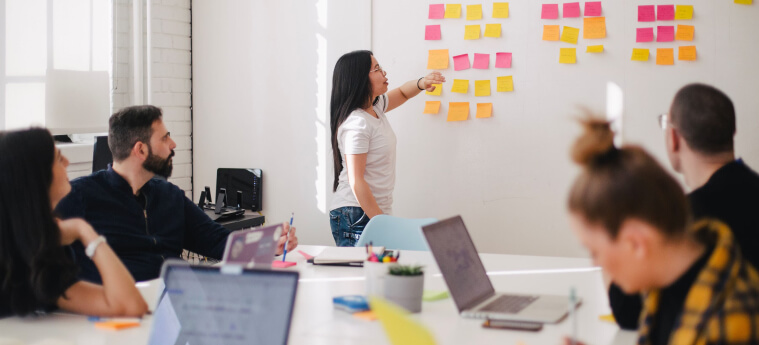 Woman placing sticky notes on a board during a team session – applying communication and decision-making skills