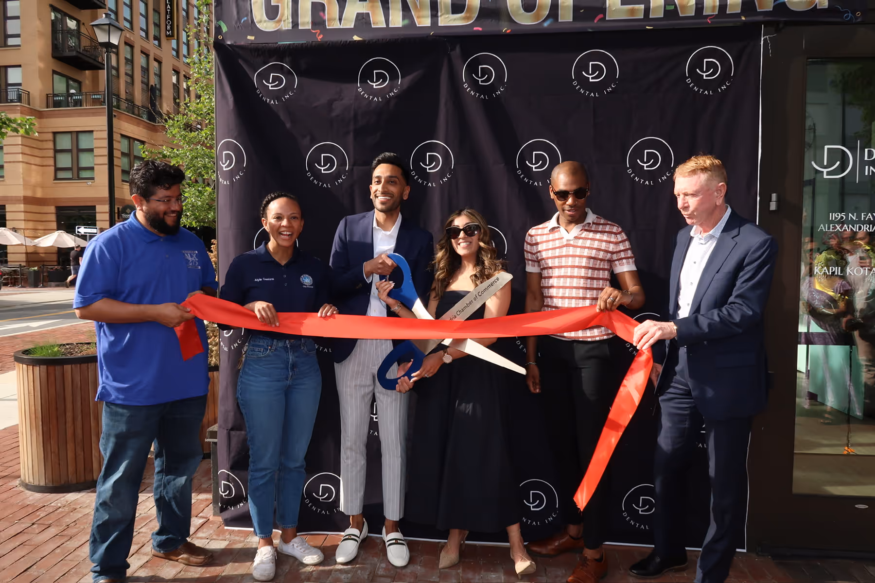 A group of people cutting a ribbon at a ribbon cutting ceremony.