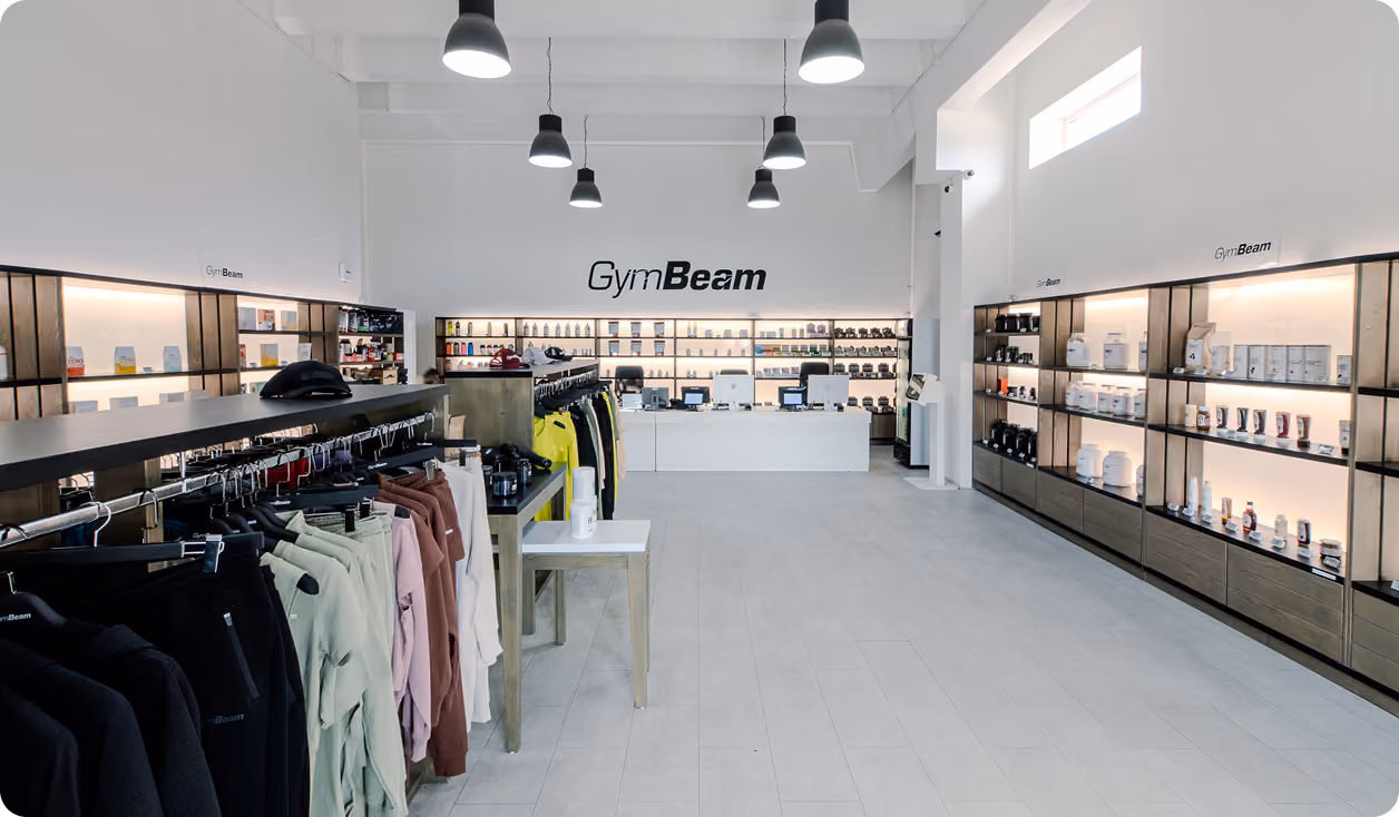Bright GymBeam store interior with shelves of supplements and racks of workout clothes.