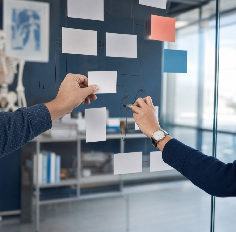 Colleagues mapping a workflow on a glass wall