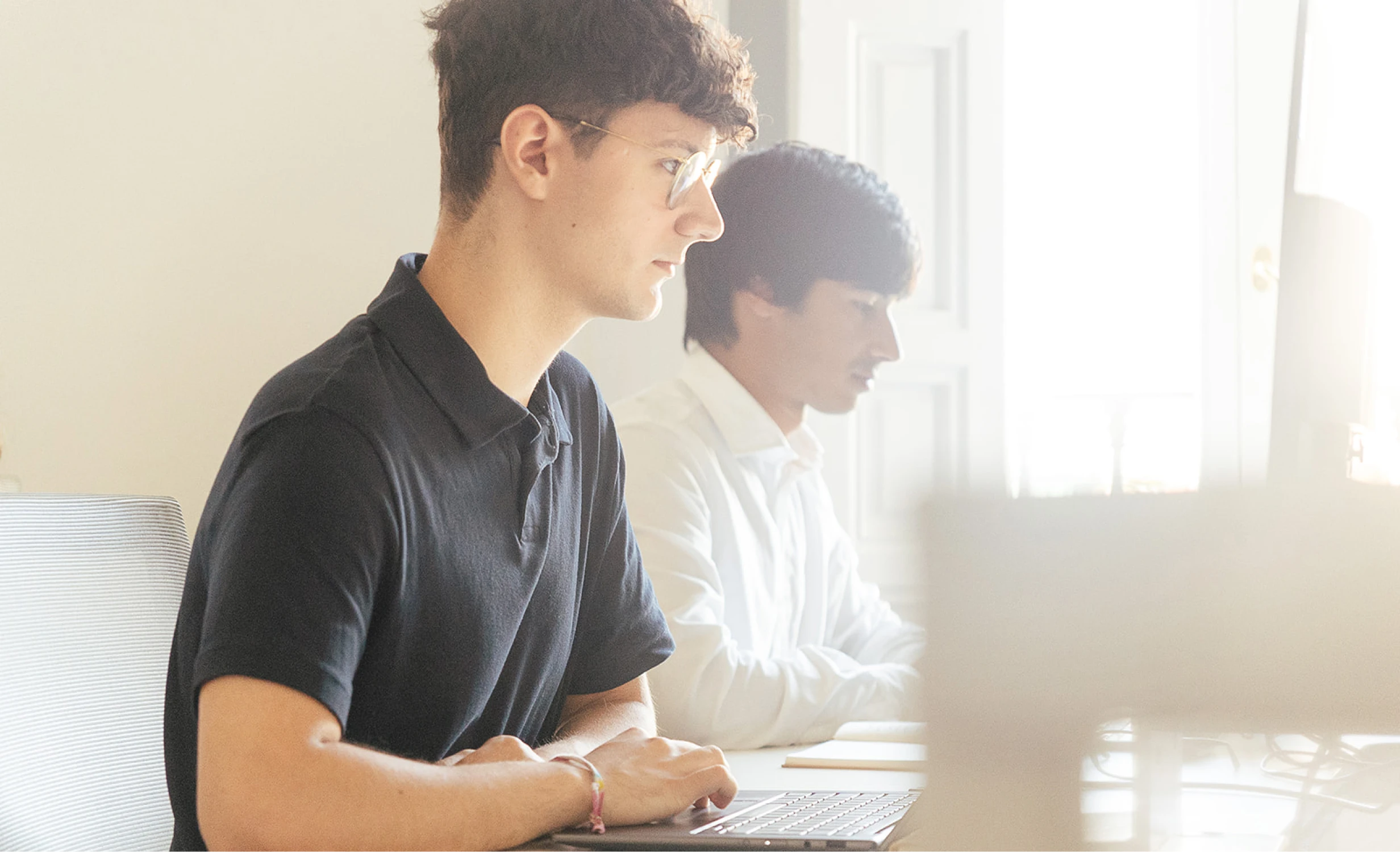 Dos jóvenes profesionales trabajando con ordenadores portátiles en la luminosa oficina Transcendent en Madrid
