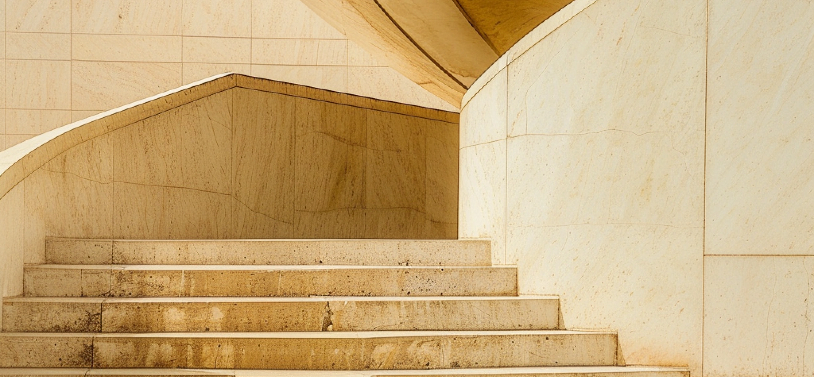 Escalera de piedra clara con paredes curvas en un edificio moderno.
