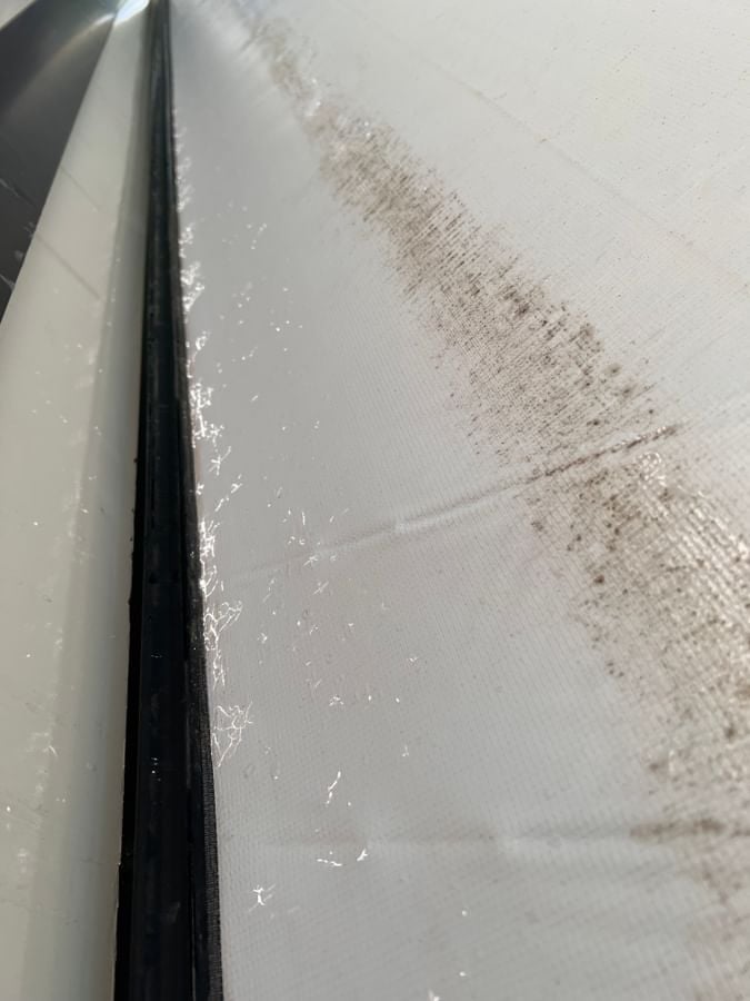 The underside of a torn awning from hail damage before it was replace by Fiberglass Worx