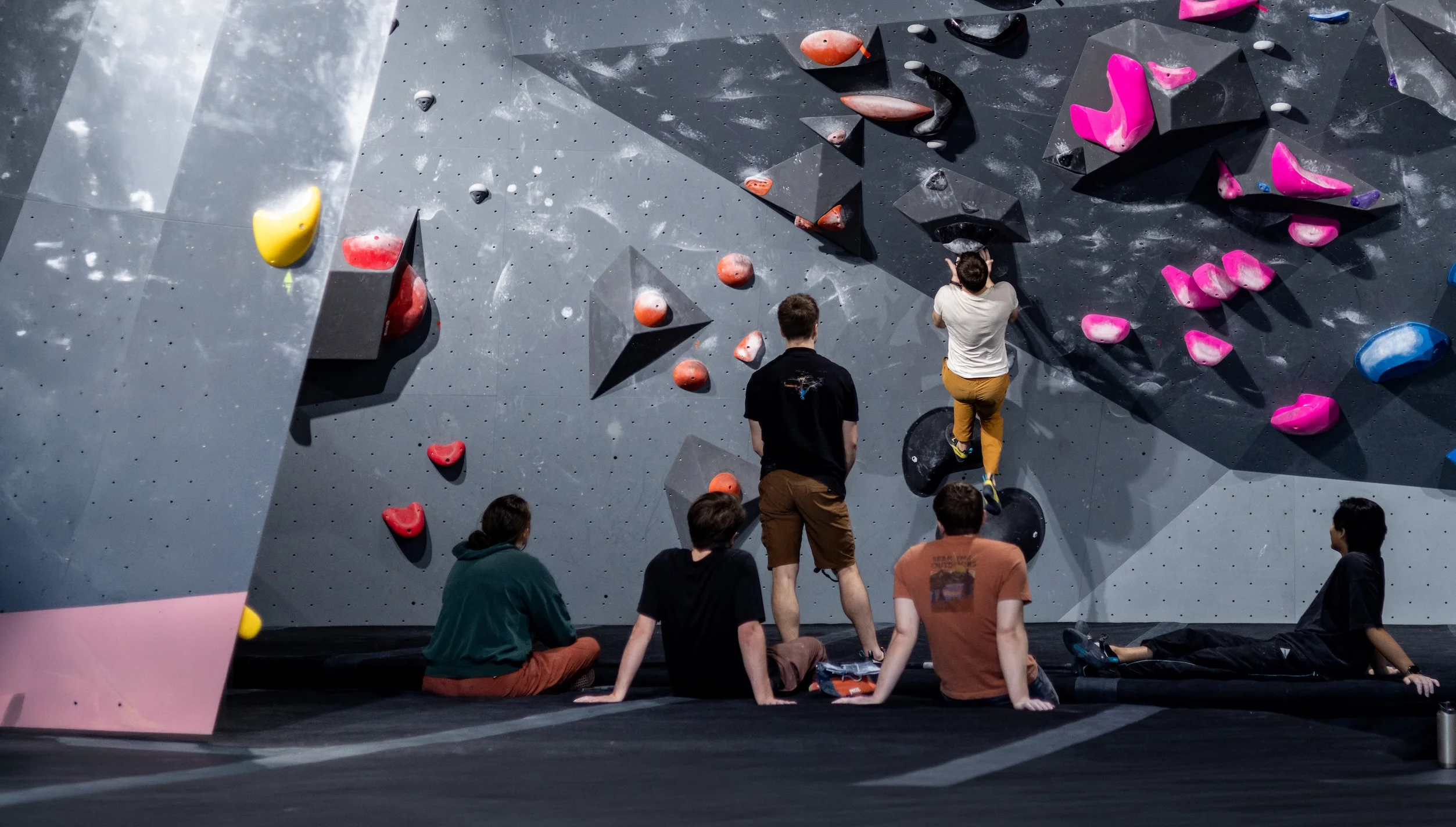 Group of climbers watching a boulderer work a problem on the bouldering wall at Shift Climbing