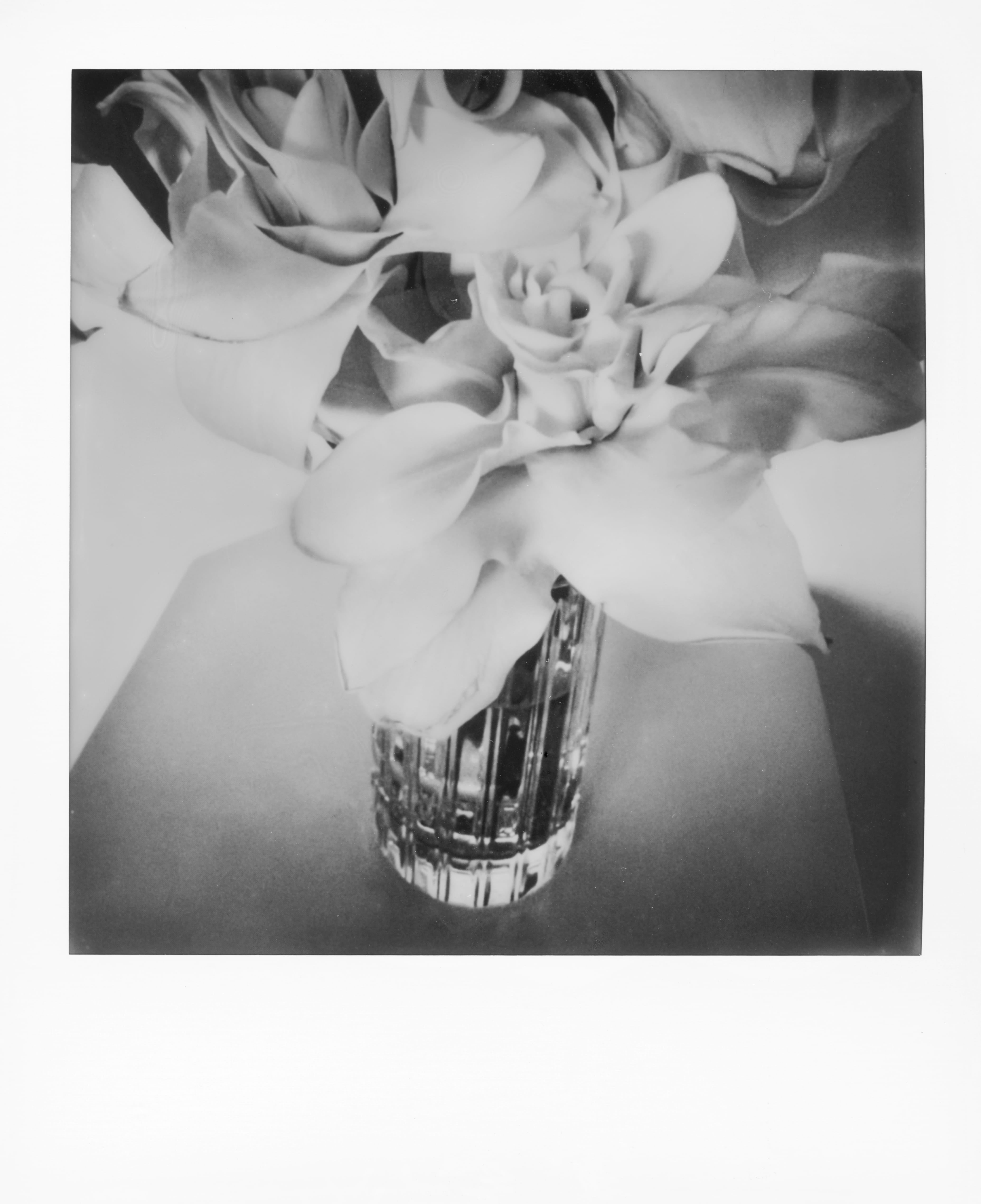 Black and white photo of roses in a textured glass vase on a table.