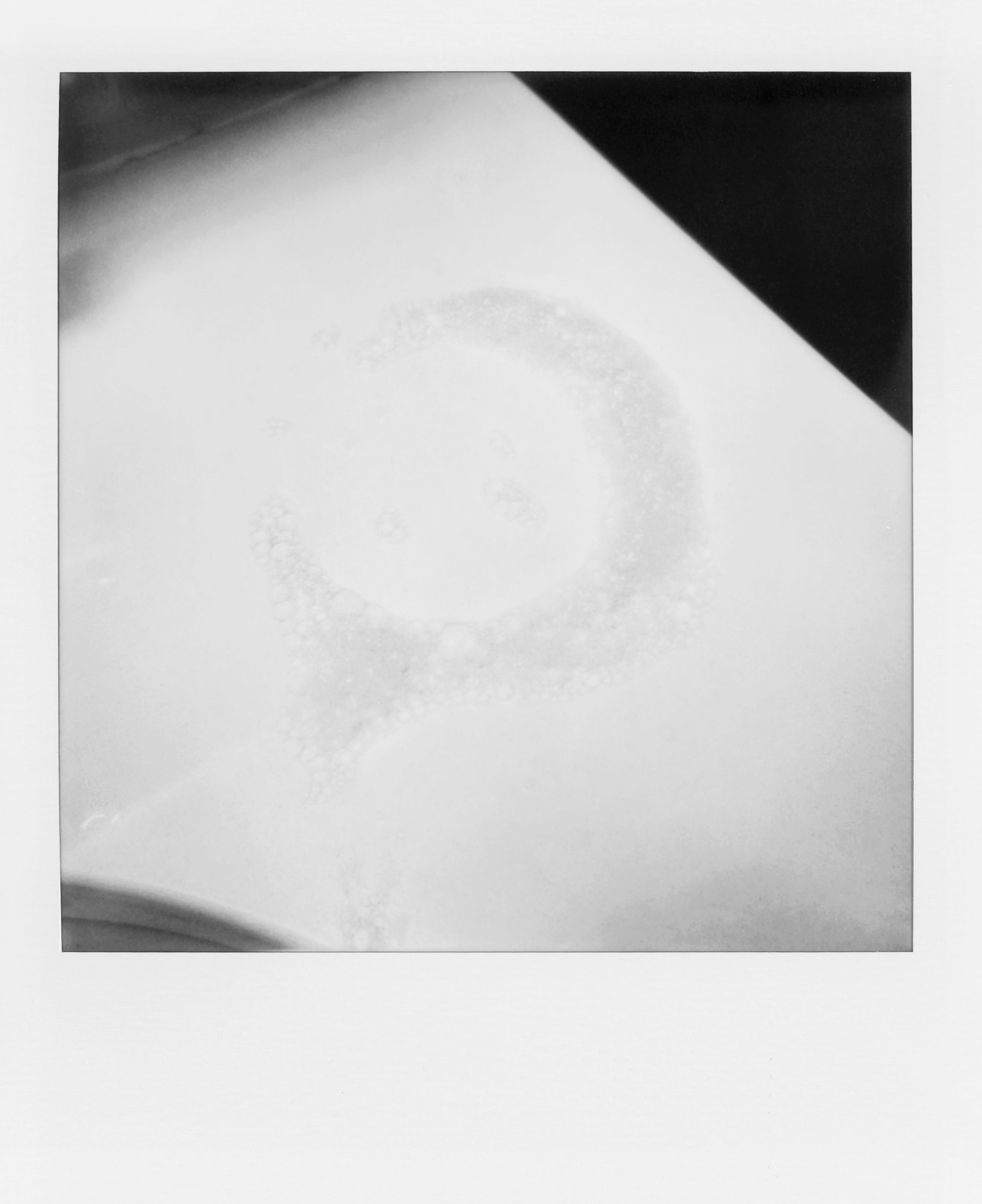 Faded bubbly ring pattern on a white surface with shadow in the upper right corner.