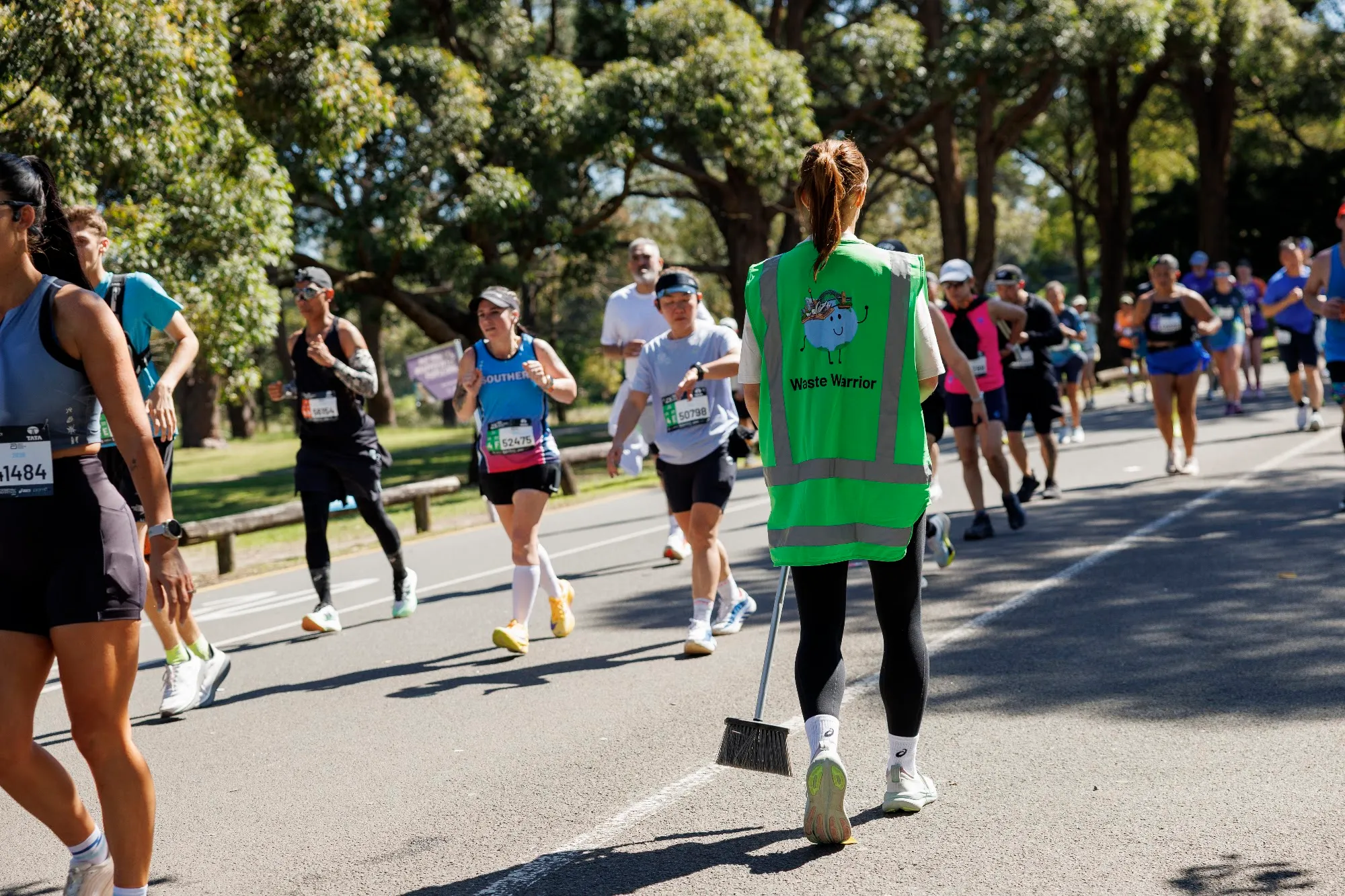 Runners streaming past a Pledge waste warrior on the TCS Sydney Marathon course