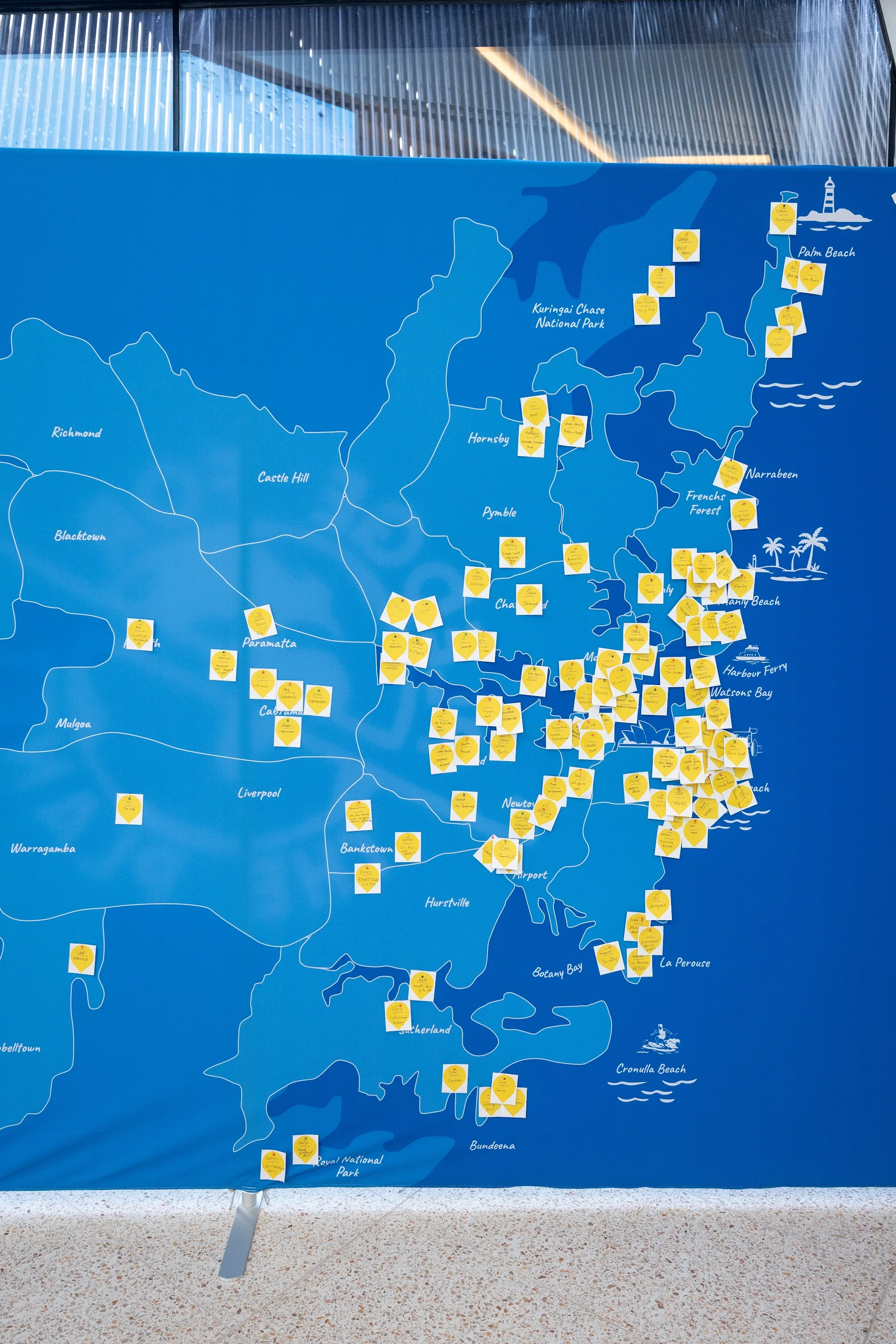 A large blue map of Sydney covered in yellow pledge notes at the JLL lobby activation