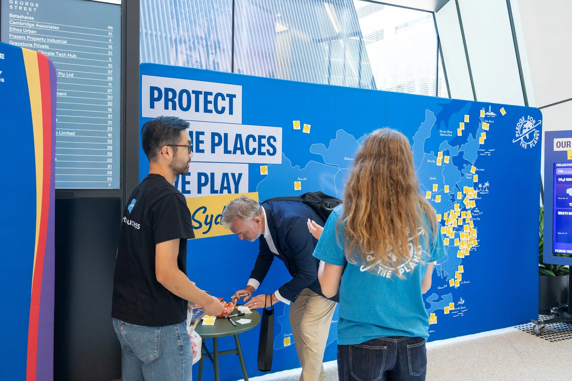 Staff writing and placing pledge notes at a lobby pledge wall