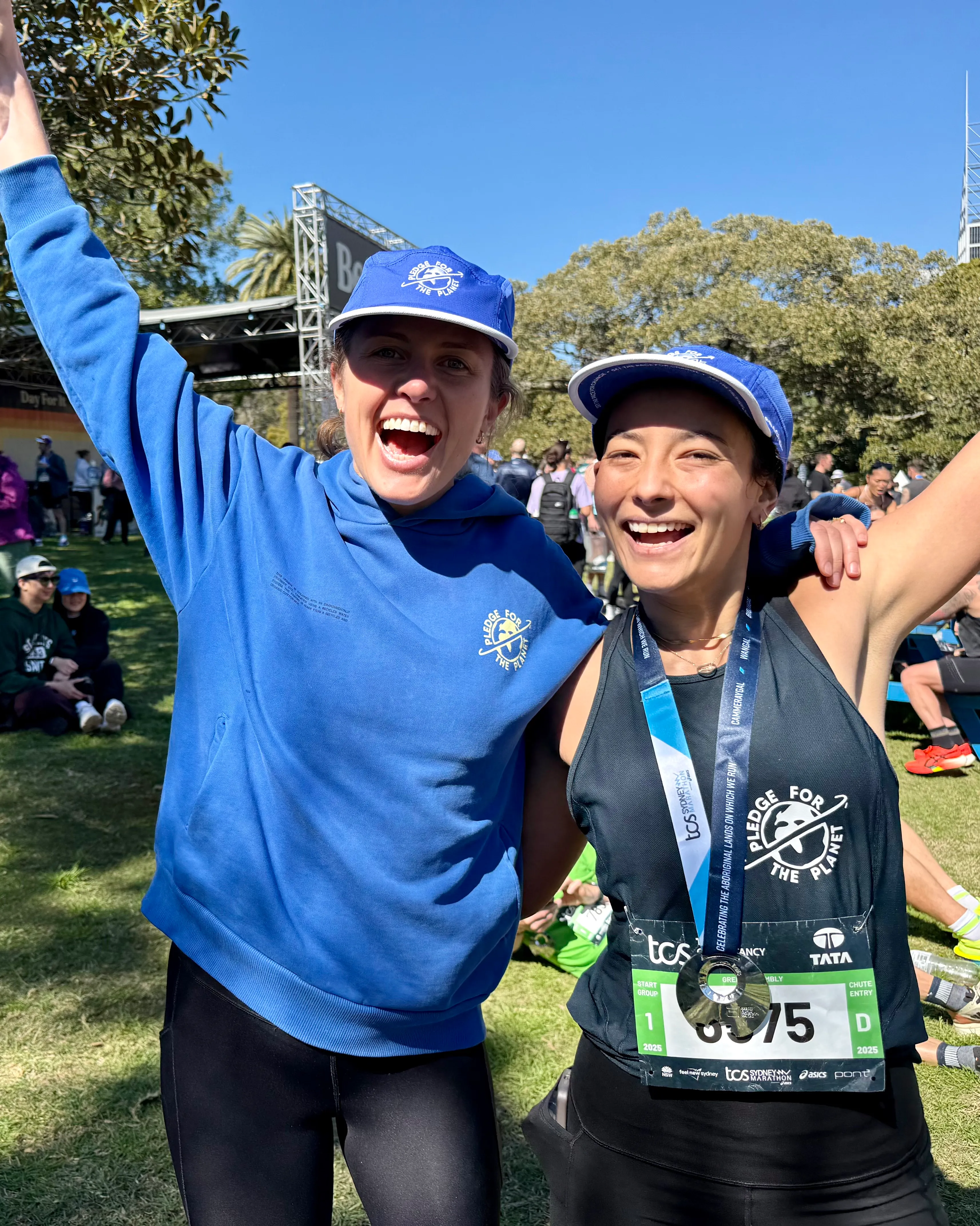 Two runners celebrating after a marathon, one wearing a medal and race bib