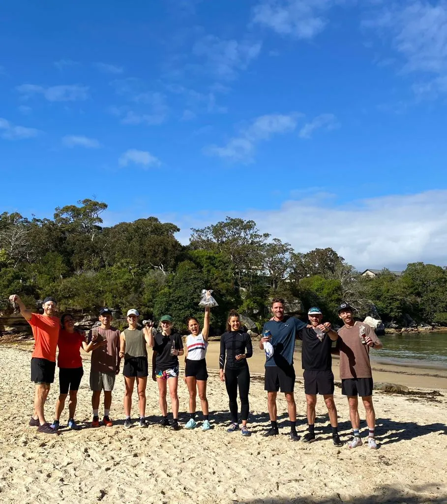 Group standing on a beach holding up bags of rubbish they collected
