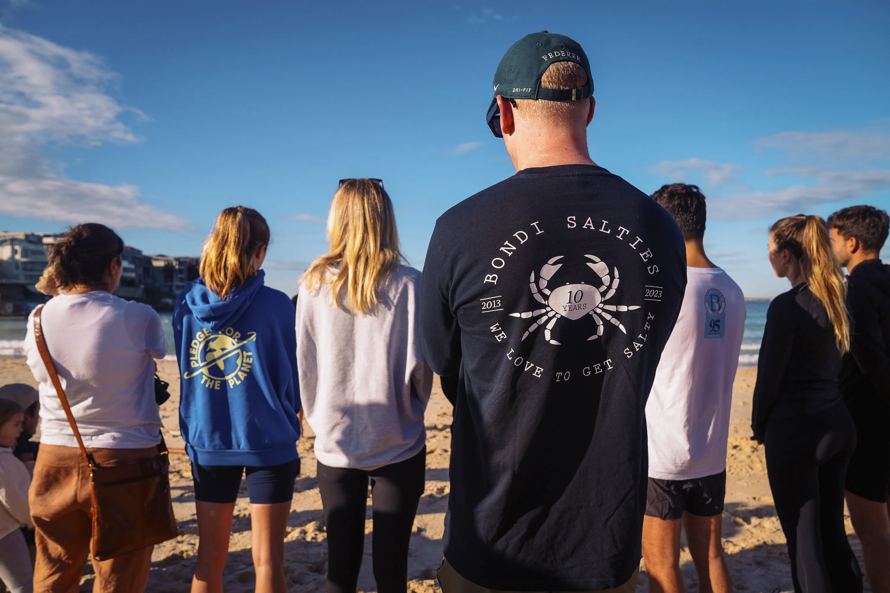 Ocean swim club members in club shirts standing on the sand at Bondi Beach