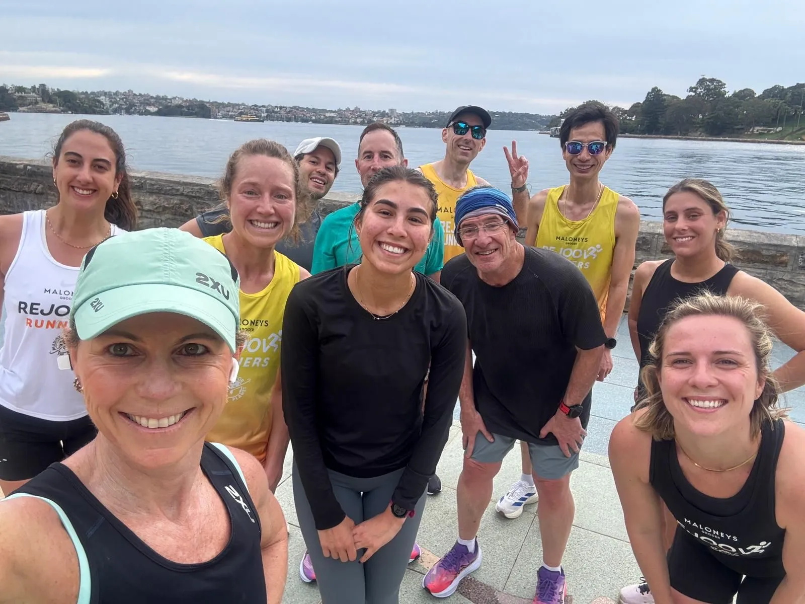 Running group posing for a group selfie beside the harbour after a run