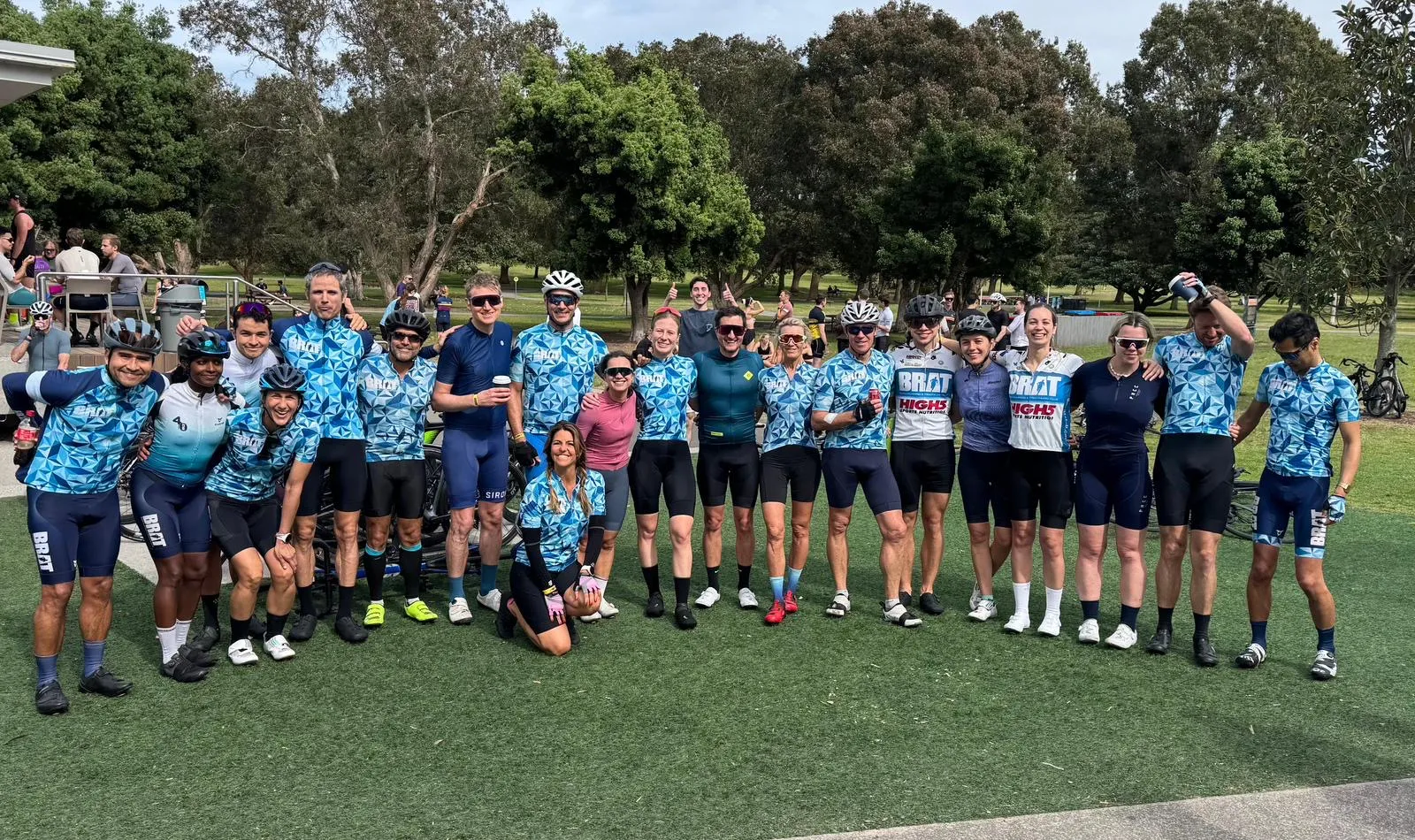 Cycling club in matching blue kit posing with their bikes on grass