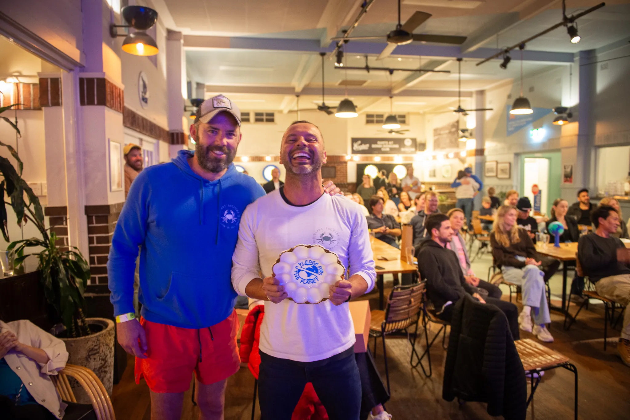 Two club members holding a trophy at a presentation night in a clubhouse