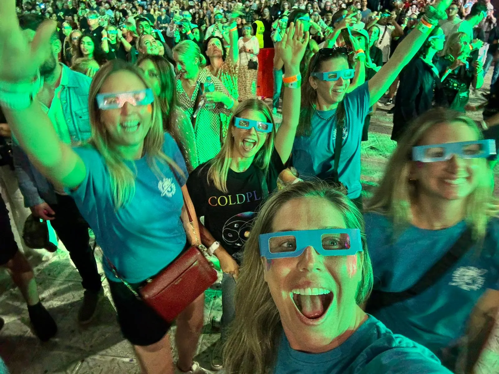 Fans in light-up glasses cheering in the crowd at a stadium concert