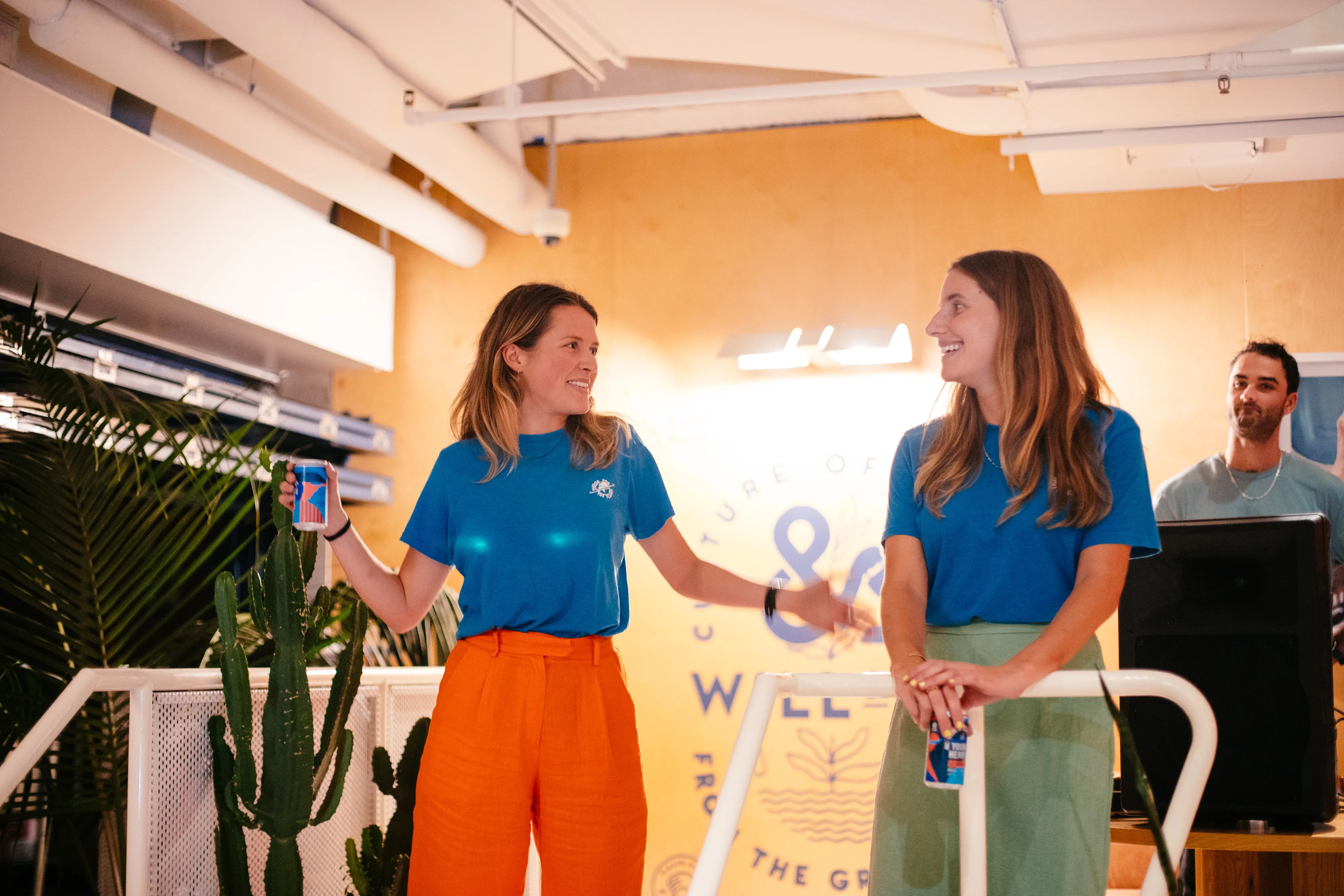 Two colleagues in matching t-shirts chatting in a bright office space
