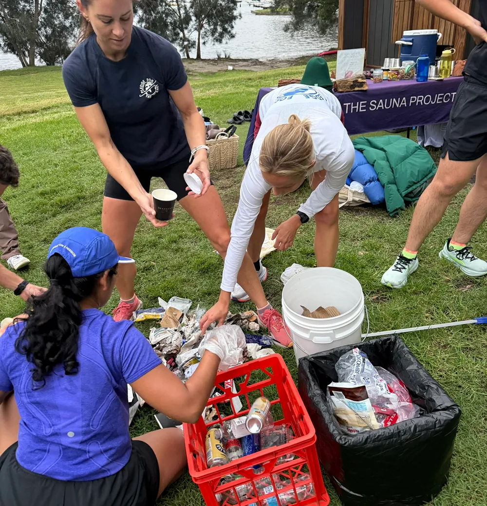 Volunteers sorting collected rubbish into crates and bins on grass by a lake