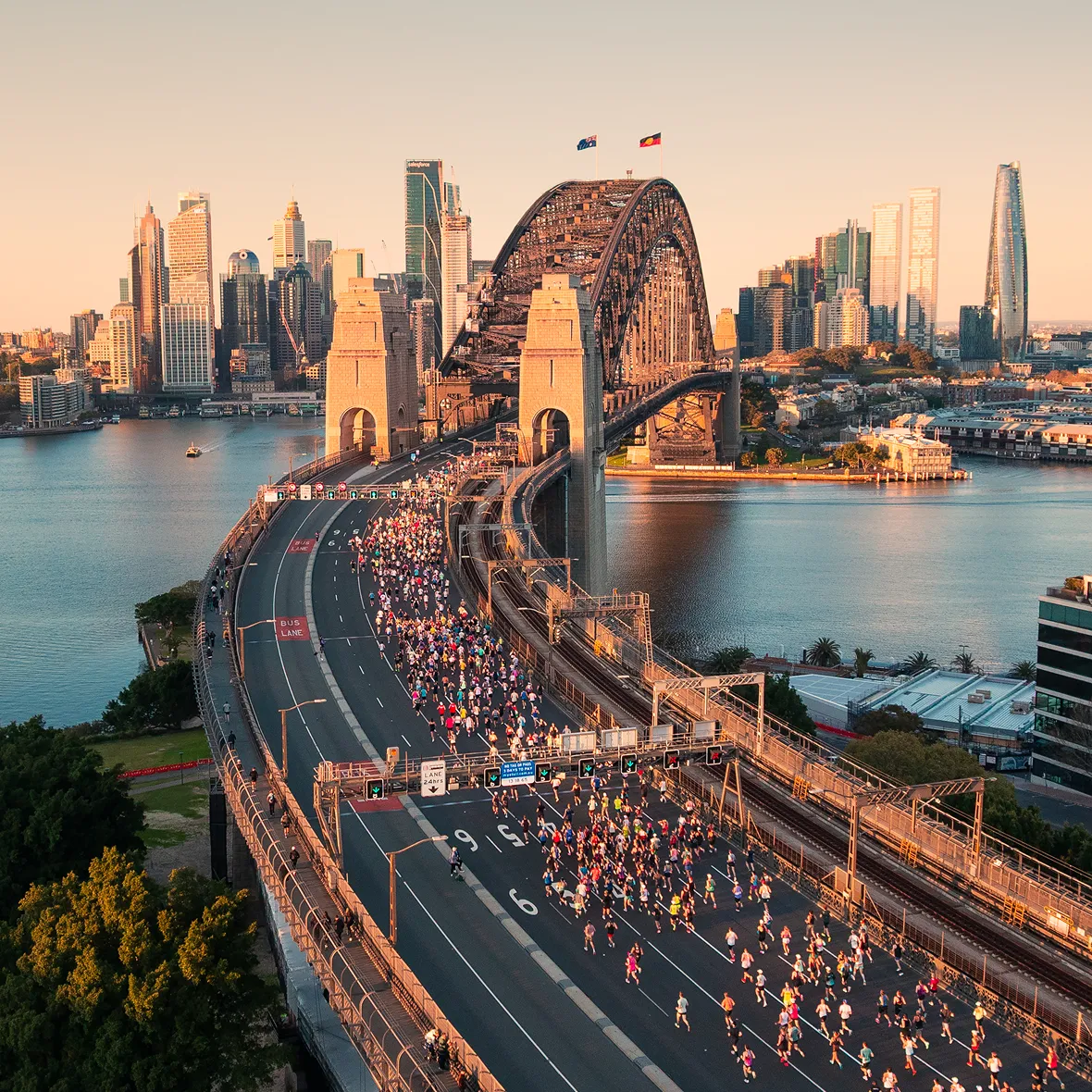 Marathon field crossing the Sydney Harbour Bridge at sunrise seen from above