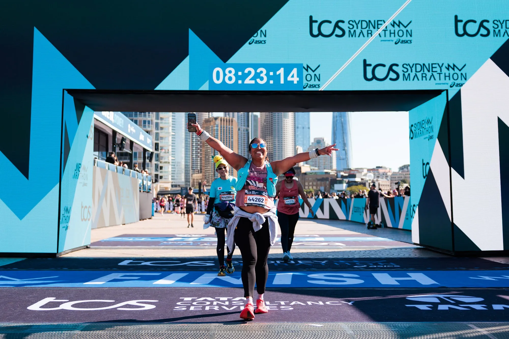 A runner celebrating under the TCS Sydney Marathon finish arch