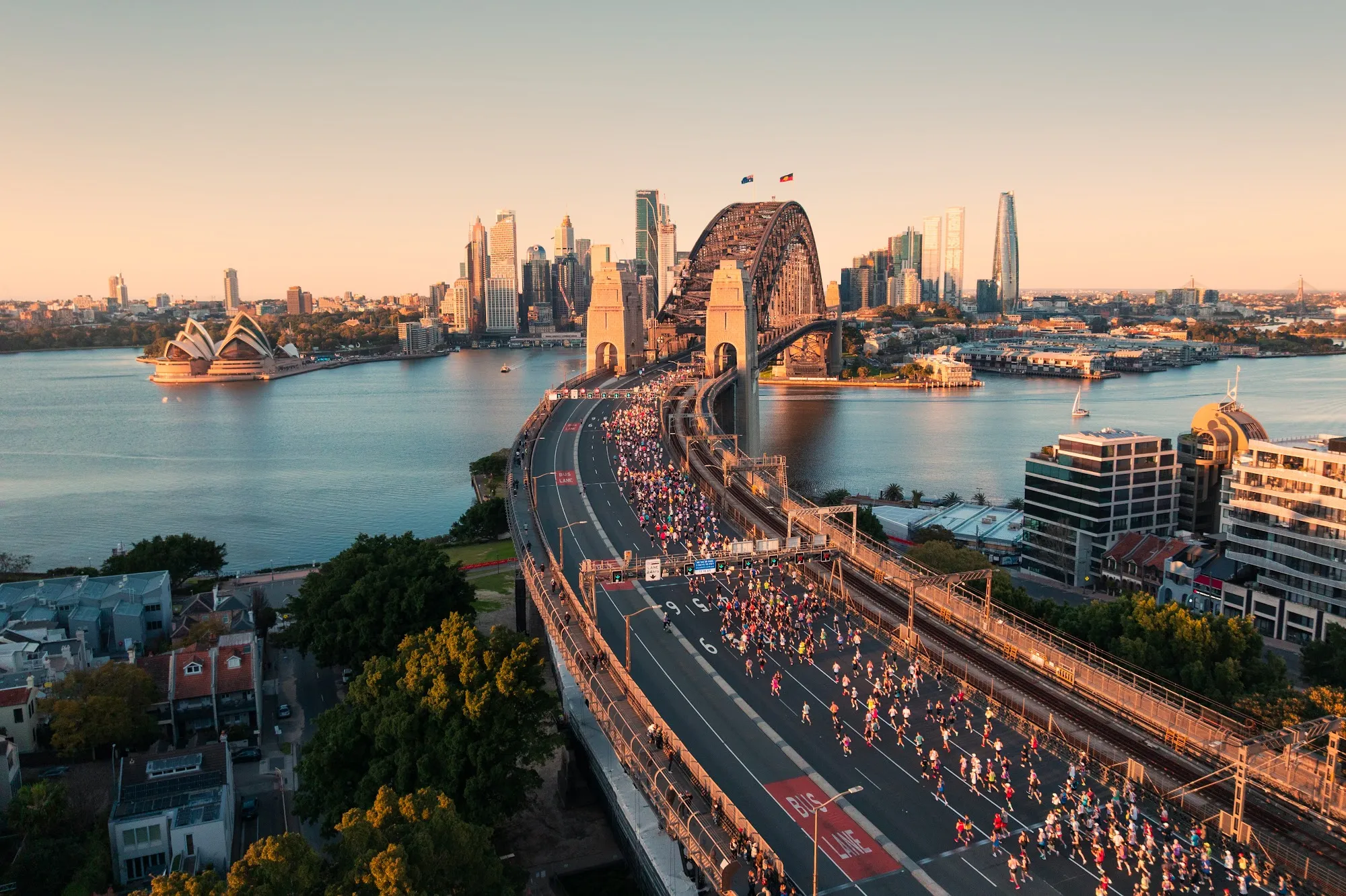 Aerial view of TCS Sydney Marathon runners crossing the Harbour Bridge with the city skyline behind