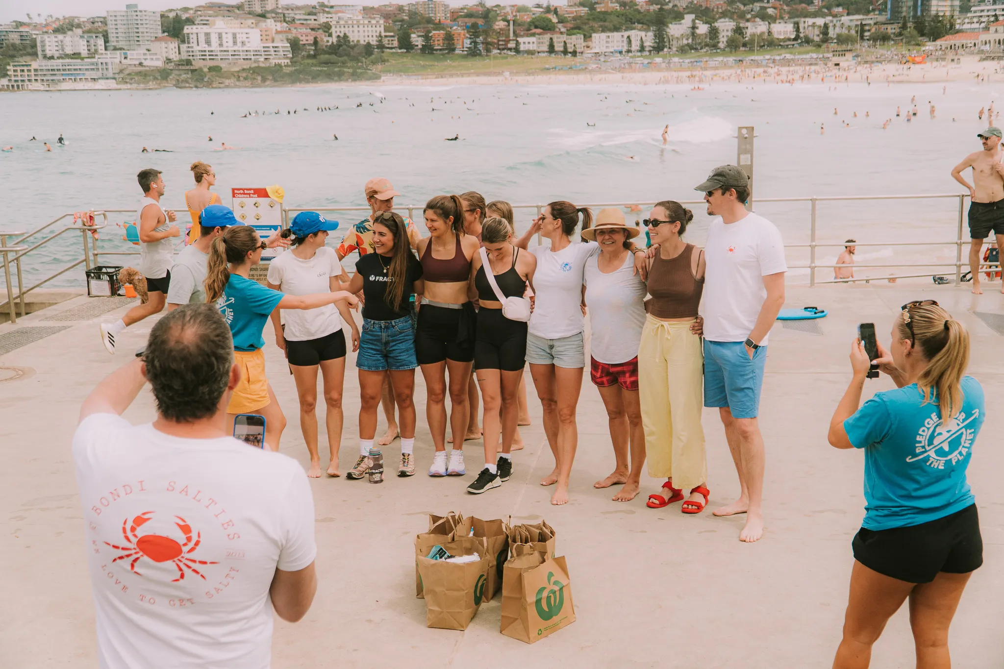 A Pledge team member in a Pledge for the Planet t-shirt talking with a club group on the Bondi promenade