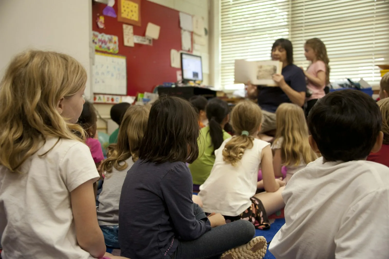 Class sitting on the floor listening to a teacher