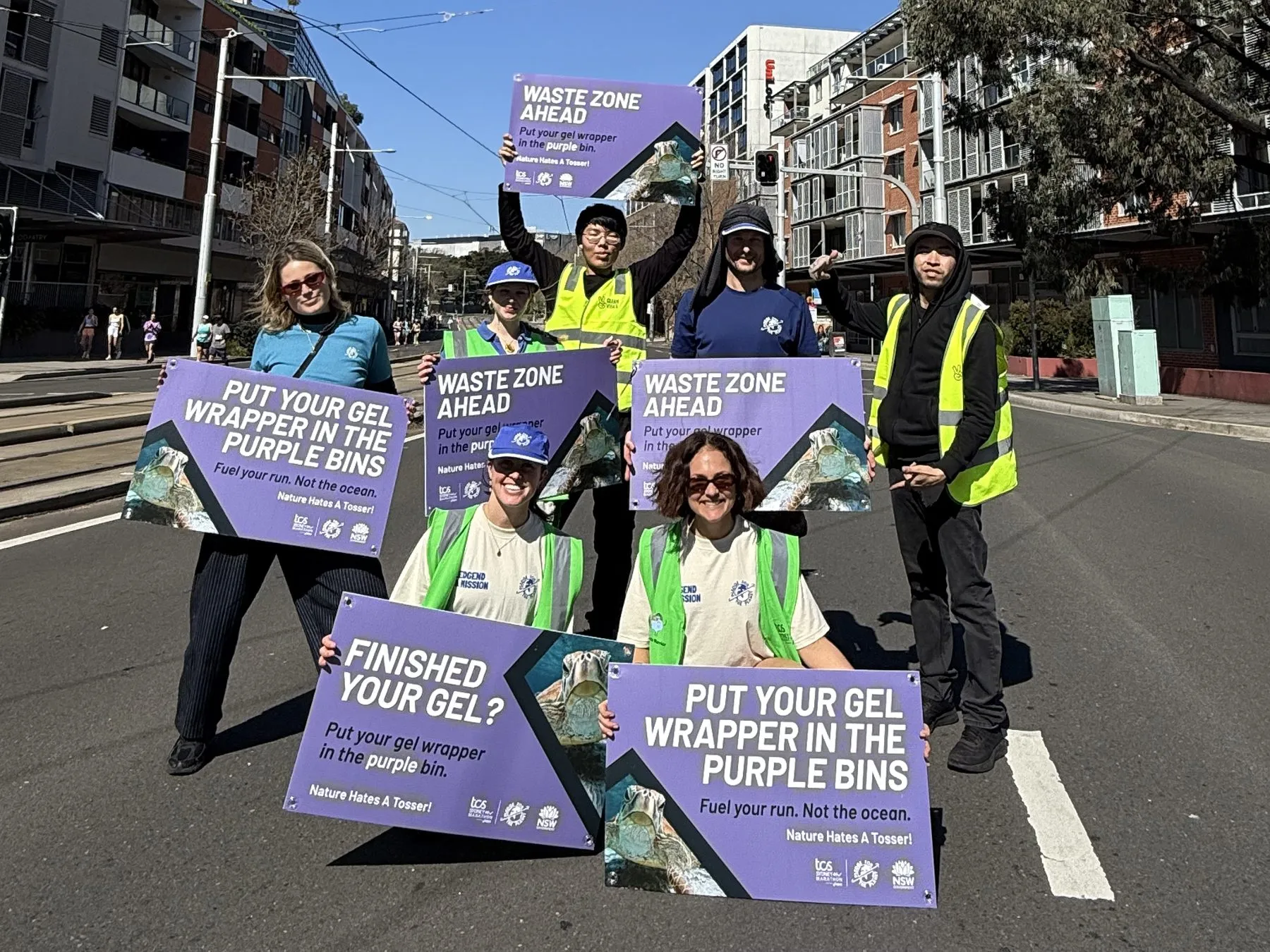 Pledge volunteers in hi-vis hold Waste Zone Ahead signs on the course at the 2026 TCS Sydney Marathon