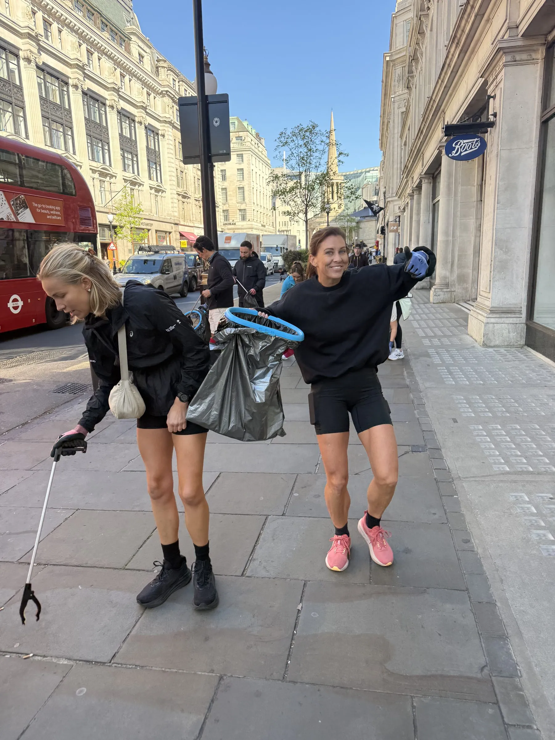 Two people carrying collected rubbish along the beach