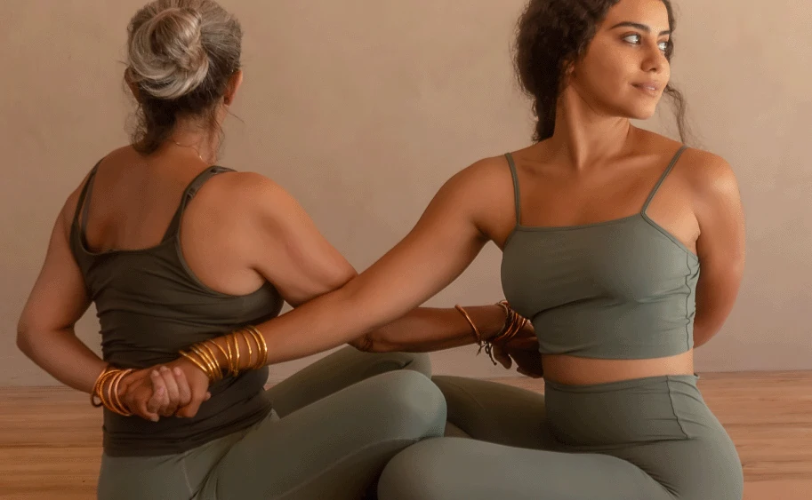 Two women practicing partner yoga at a serene retreat, showcasing the best yoga in Jimbaran at Balquisse Heritage Hotel Bali.