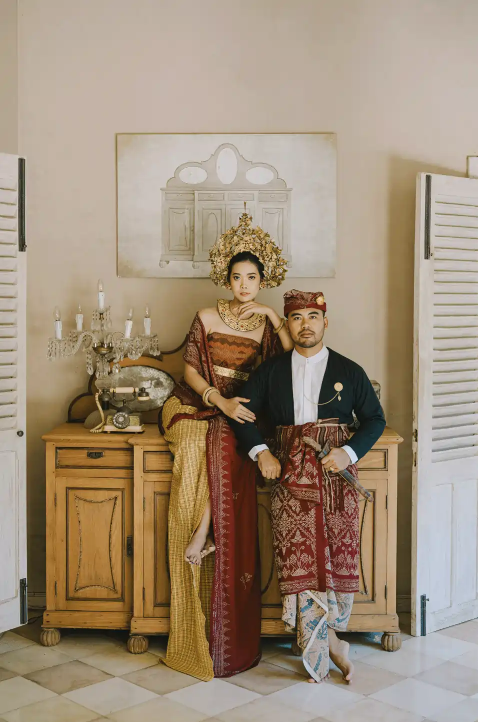 Couple in traditional Balinese attire posing indoors for prewedding engagement photoshoot at prewedding venue hotel in Jimbaran.