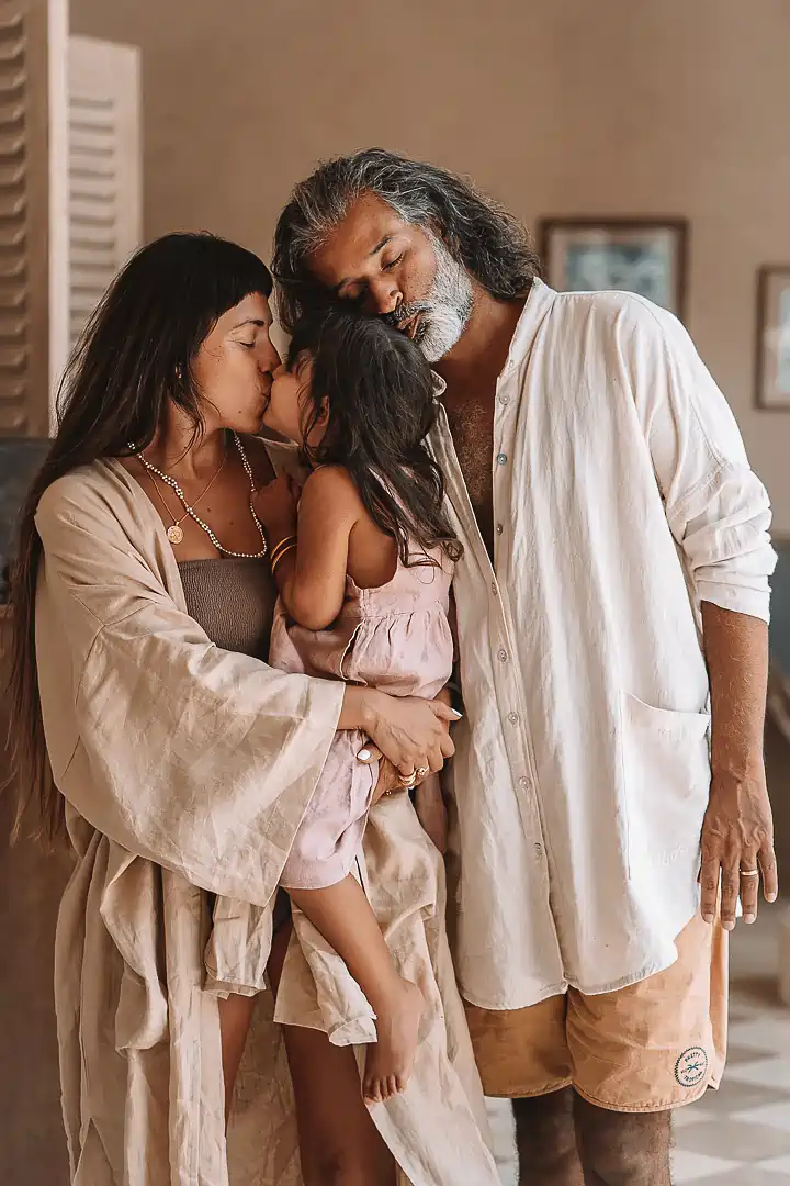 A family embraces during a heartwarming moment inside a cozy, earth-toned room—perfectly capturing the warmth of a family photoshoot at the photography venue hotel in Jimbaran at Balquisse Heritage Hotel Bali.