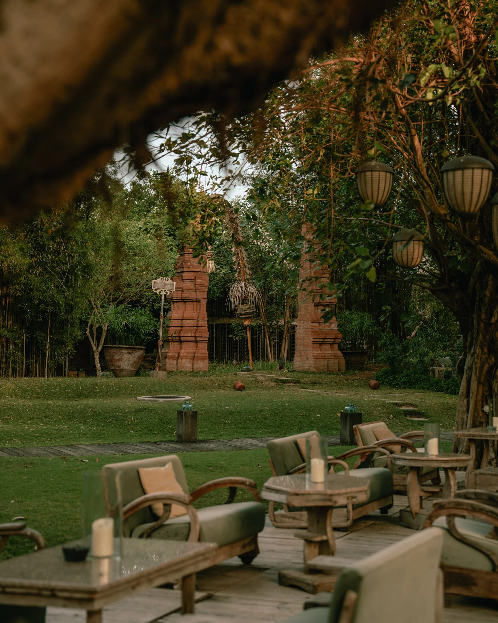 Outdoor lounge terrace overlooking traditional Balinese red brick gates and lush green gardens at Balquisse Heritage Hotel, Jimbaran.