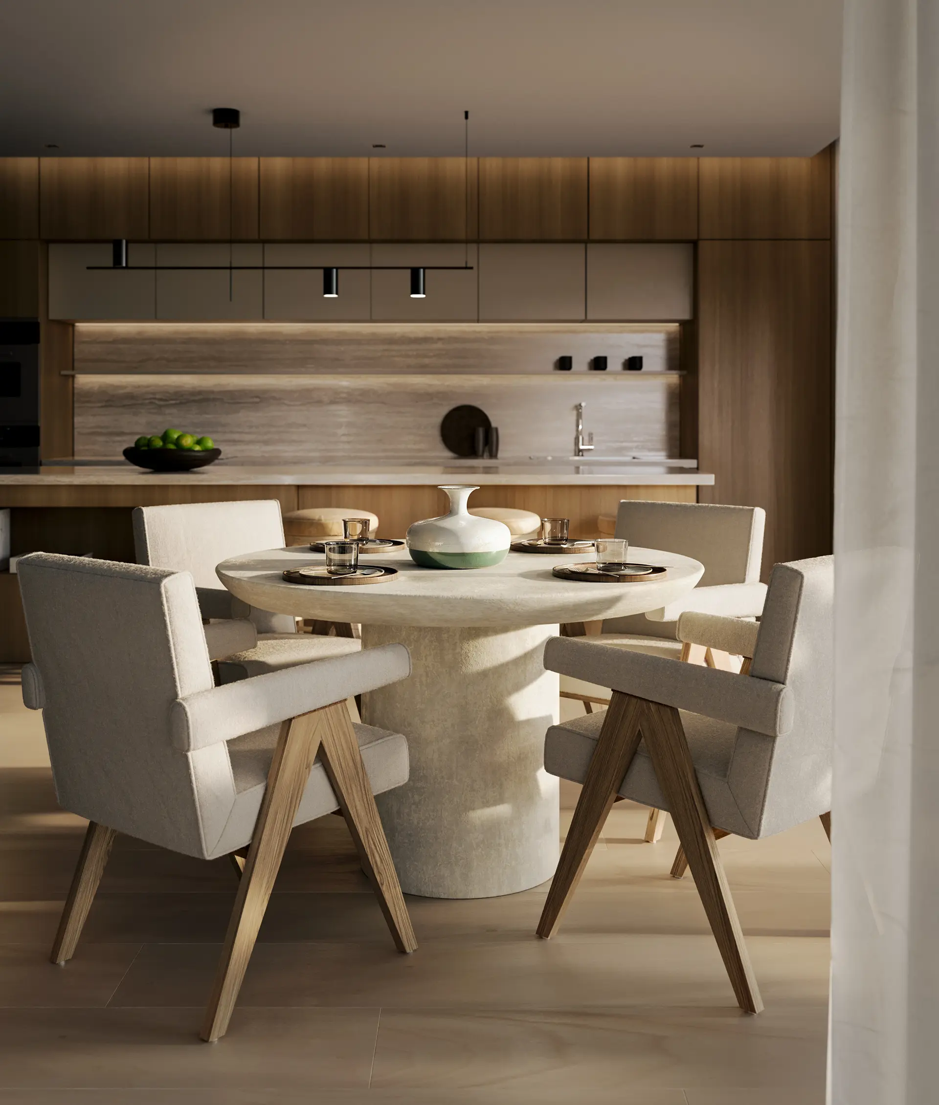 Modern dining room with a round stone table, four upholstered chairs, and a minimal kitchen background.