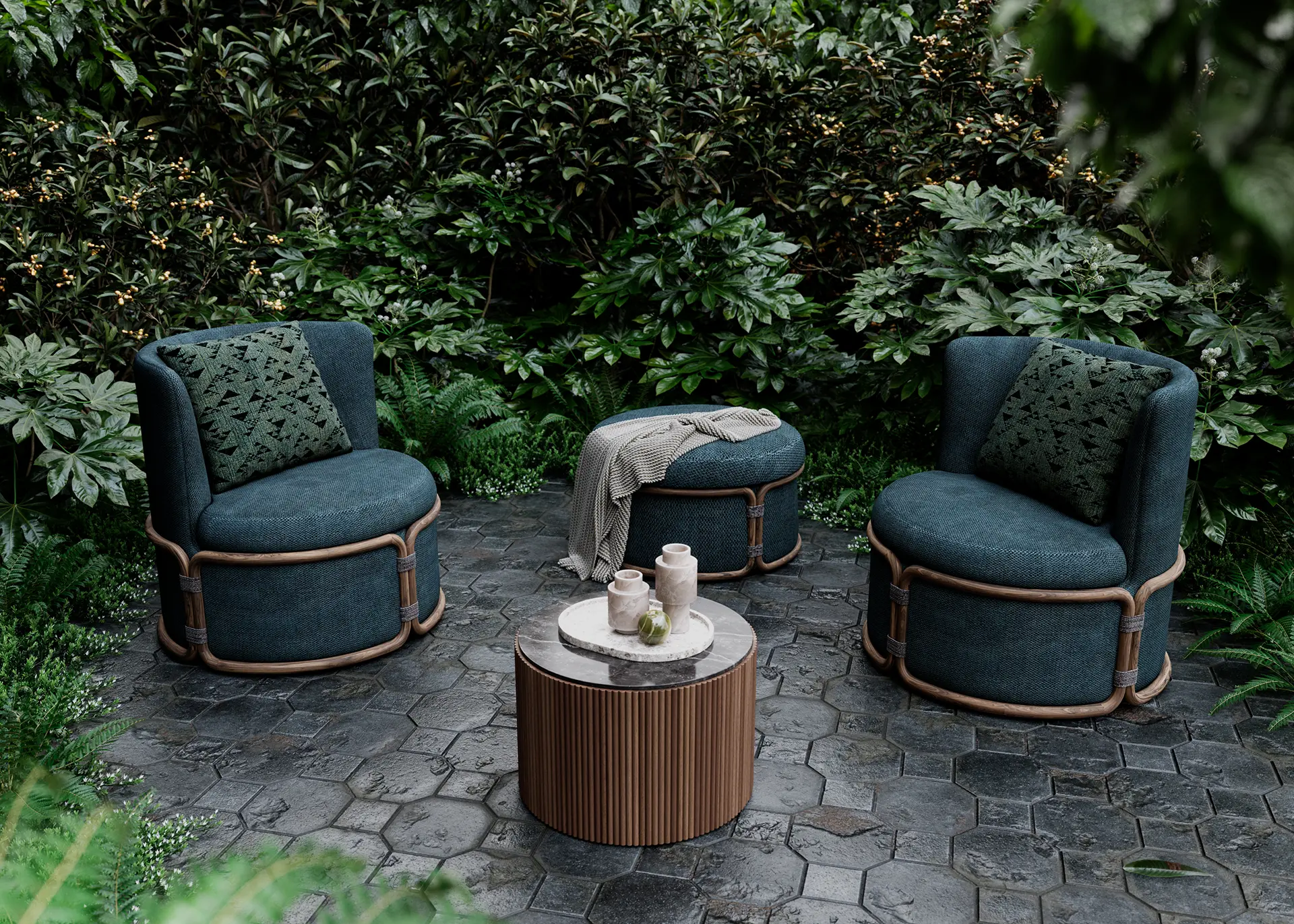 Outdoor lounge area with two dark green armchairs and a round coffee table on a stone patio, surrounded by lush greenery.