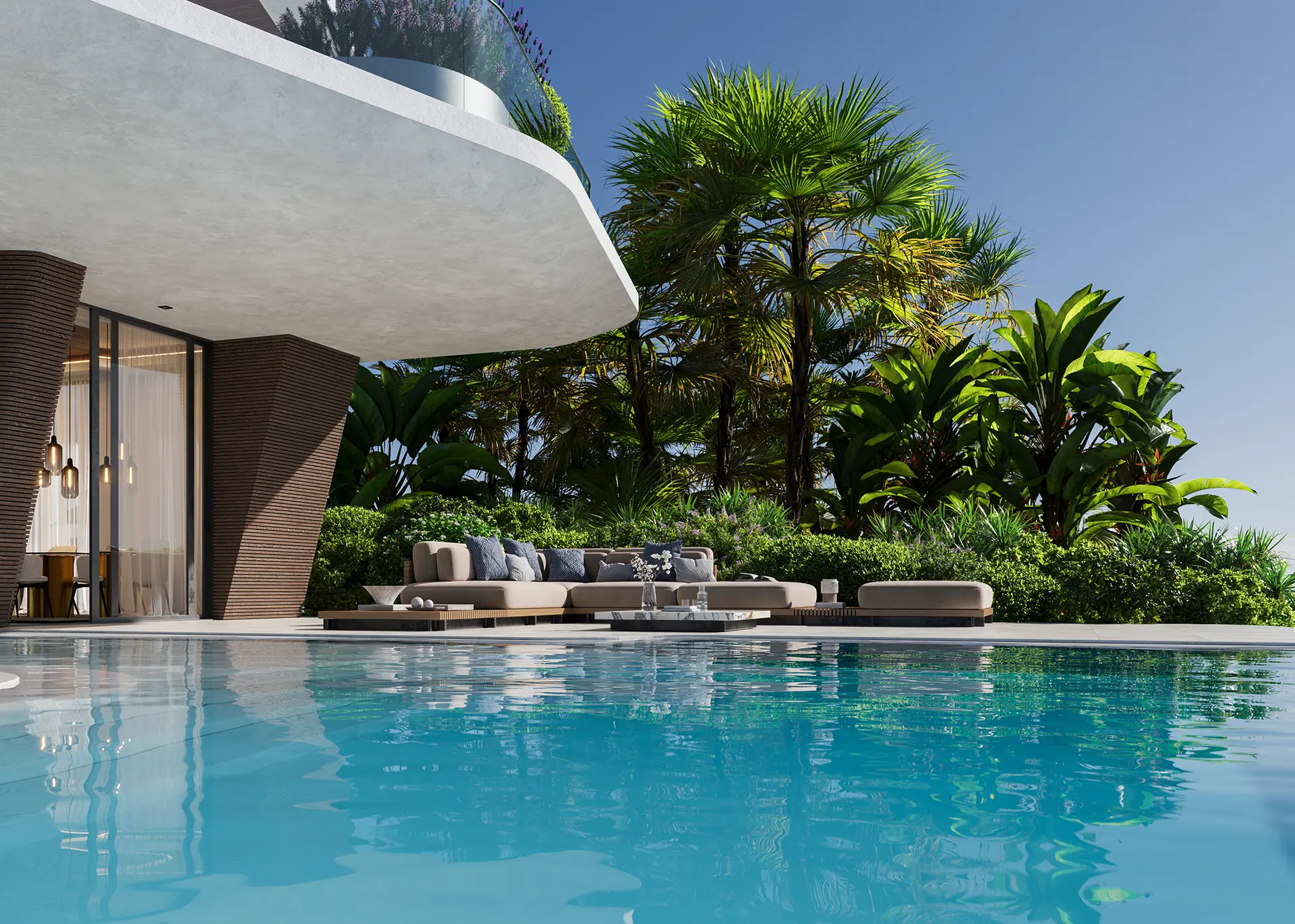 Pool-level view of the outdoor lounge area with a neutral sectional sofa set against a backdrop of palms and tropical foliage