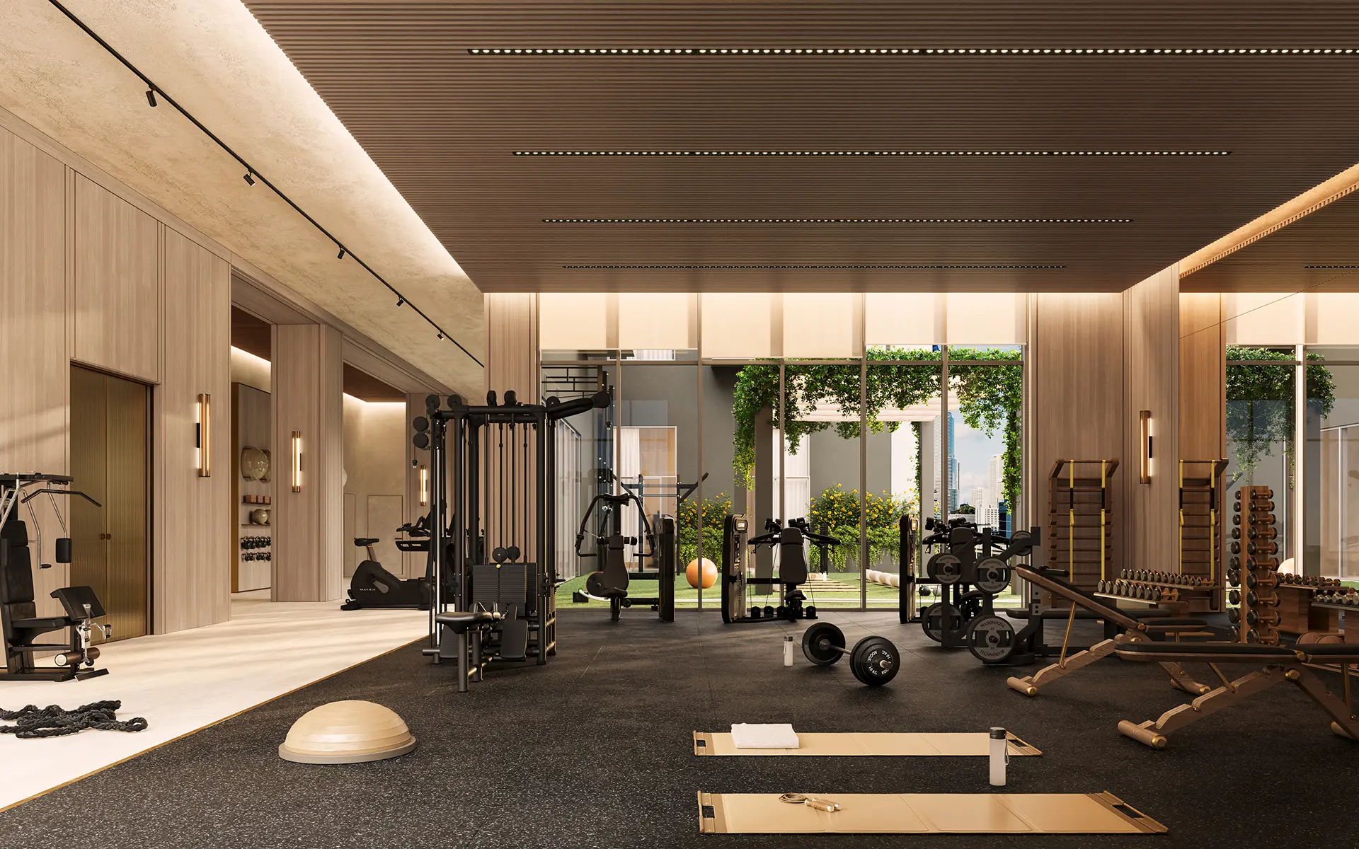 Fully equipped fitness center with strength machines, free weights, and floor-to-ceiling windows overlooking a green courtyard.