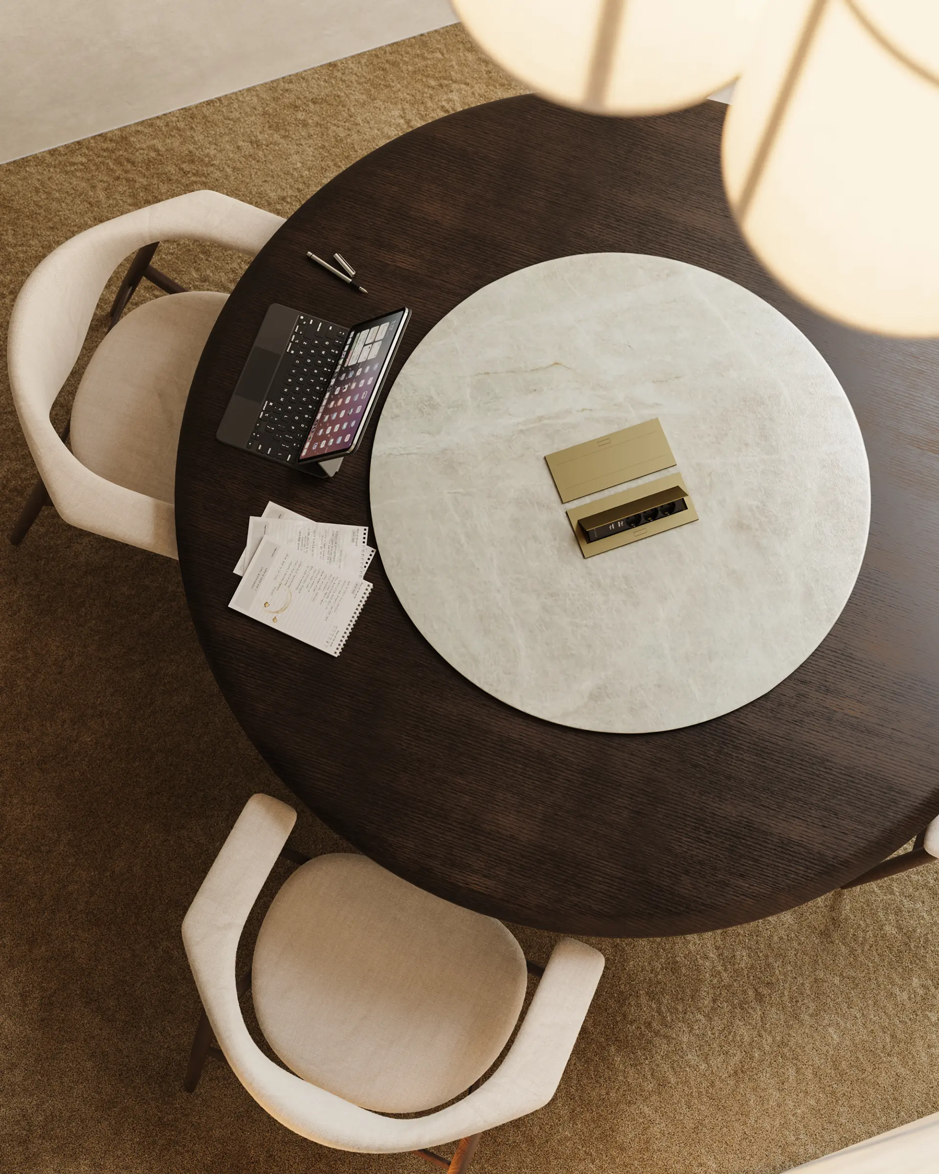 Round dark wood meeting table with a white circular centerpiece, two beige chairs, a tablet, papers, and pens.