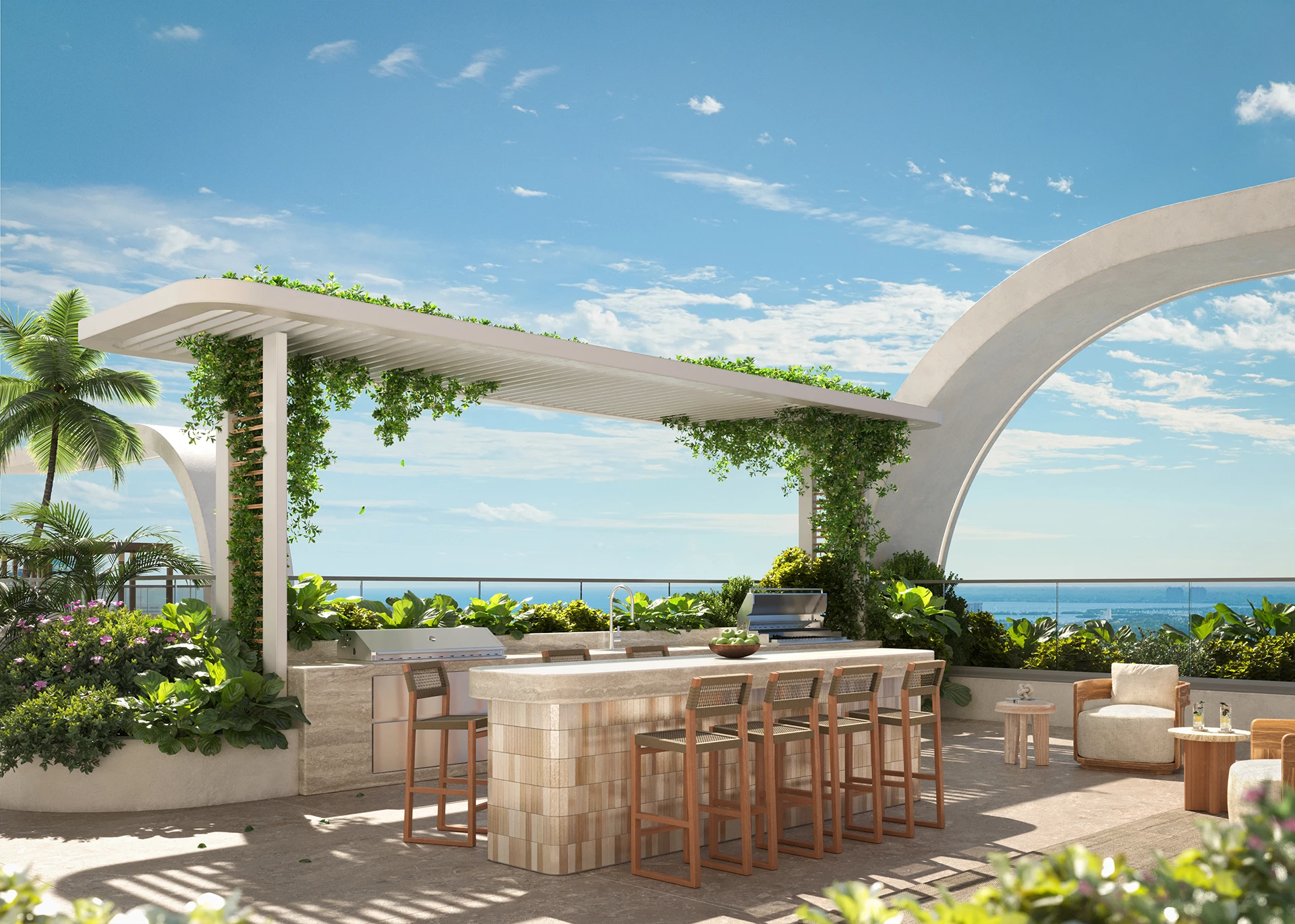 Modern rooftop outdoor BBQ kitchen and seating area with bar stools, greenery, and ocean view under blue sky.
