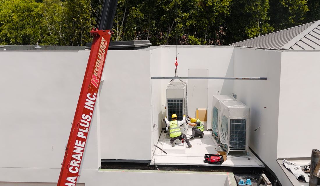 Rhino Air crew craning a Daikin VRV condenser into a concealed rooftop equipment well on a Brentwood estate