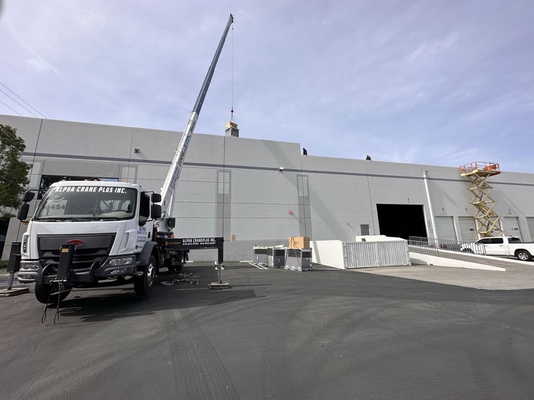 Crane setting rooftop HVAC equipment on an industrial food-production facility — Rhino Air commercial installation