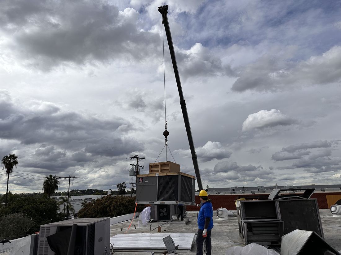 Crane lifting a new Rheem Commercial rooftop package unit onto an operating studio facility in Compton, Los Angeles — HVAC replacement by Rhino Air