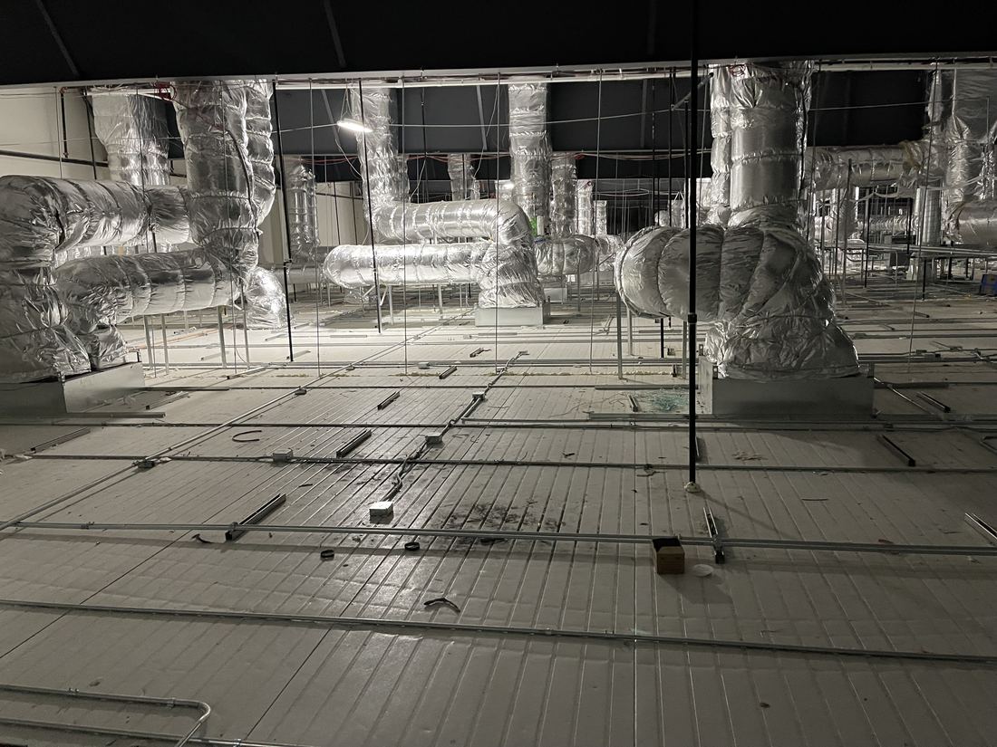 Insulated trunk ductwork above the ceiling grid of a large manufacturing facility in San Bernardino County — full HVAC installation by Rhino Air