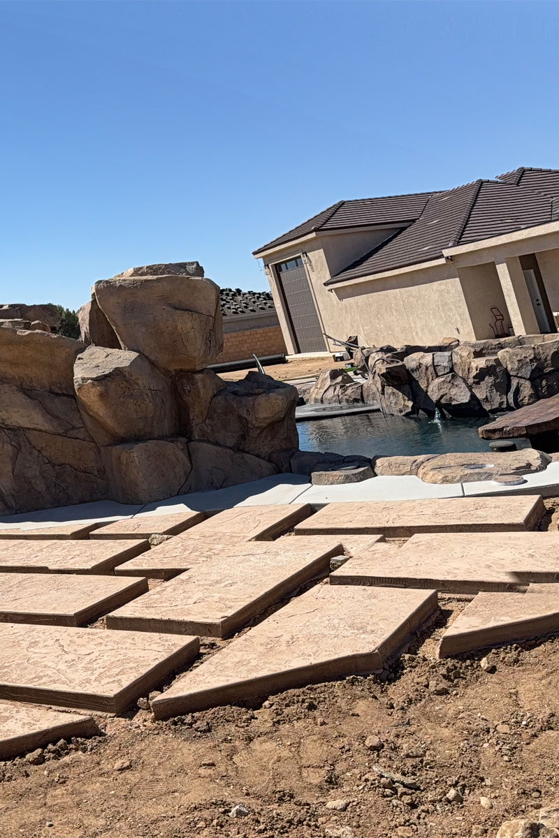 A patio is under construction, with pavers being laid on the ground.