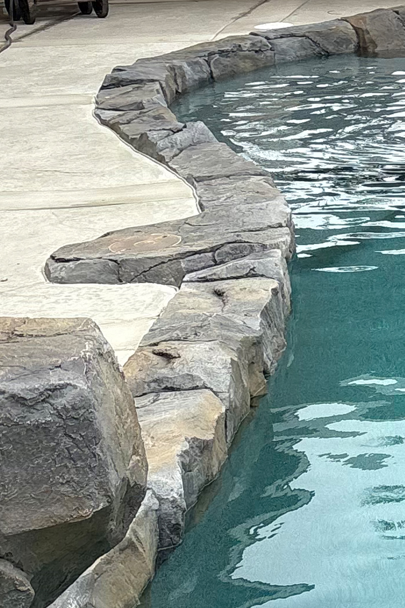 The stone edging or coping around a swimming pool.