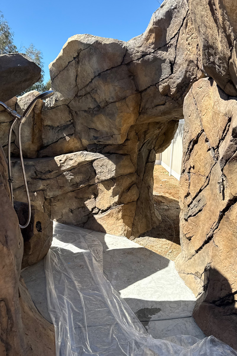 A shower area seamlessly integrated and built into a wall or structure made of large, natural stones.
