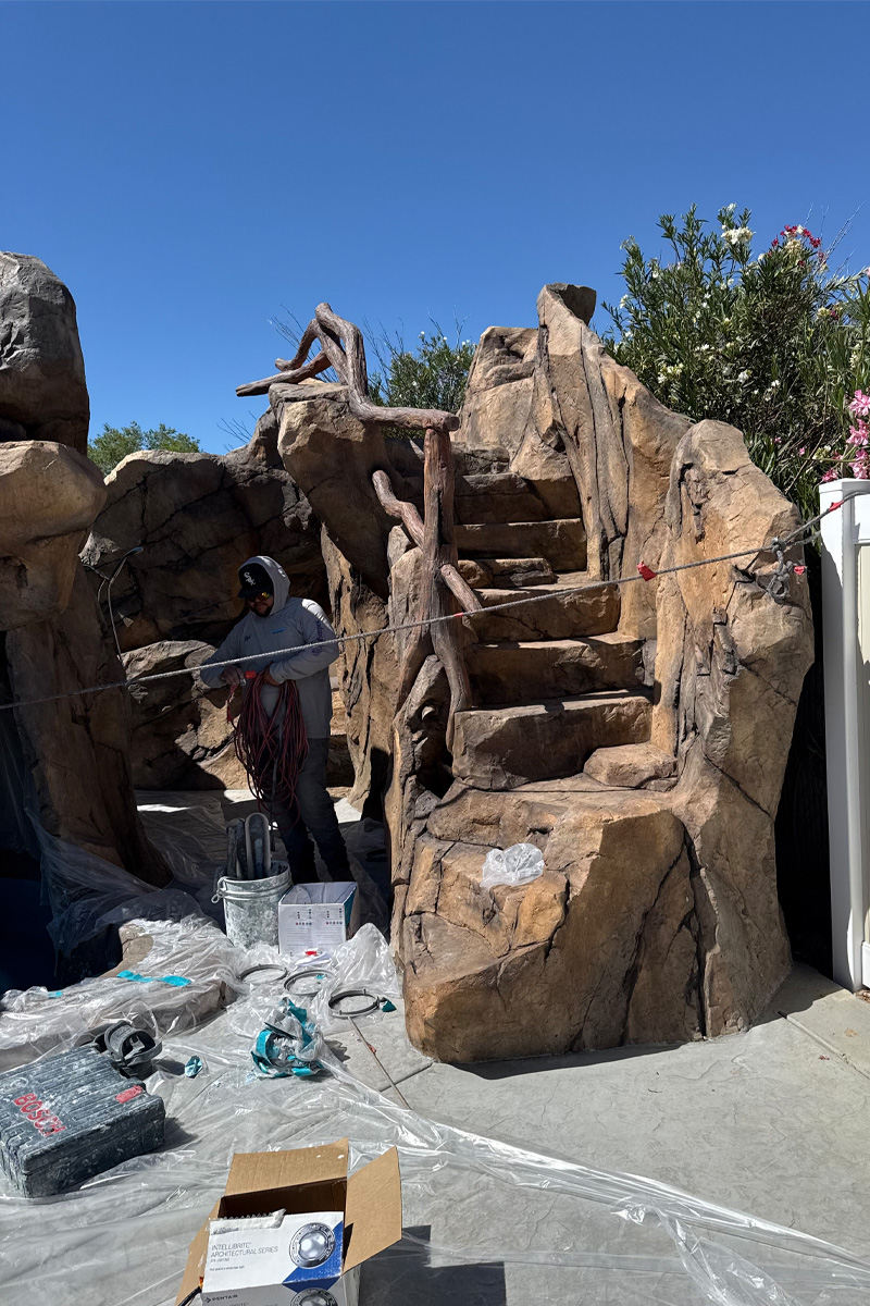 tone steps for a swimming pool under construction, with a worker holding ropes.