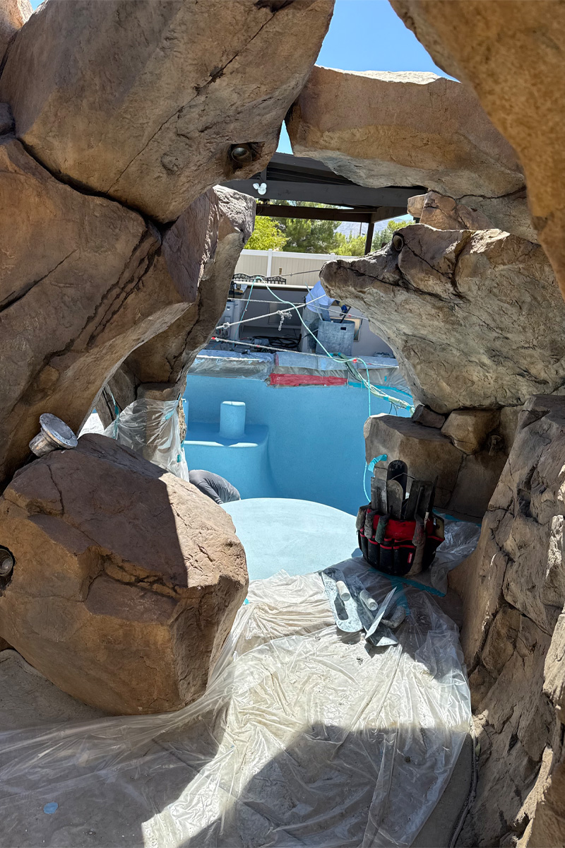 Large stones are visible next to a swimming pool that is currently being painted